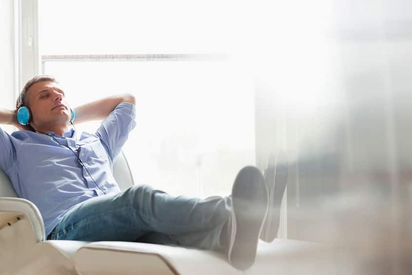 Full-length of relaxed Middle-aged man listening to music at home